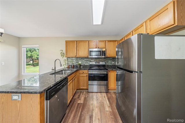 29719 Monterey Cir, Farmington, MI 48336 - kitchen with appliances with stainless steel finishes, dark wood-style floors, a peninsula, dark stone counters, and decorative backsplash