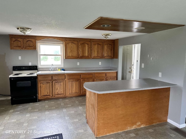 2252 N M-18 Rd, Beaverton, MI 48612 - kitchen with range with electric stovetop, brown cabinets, light countertops, and a peninsula