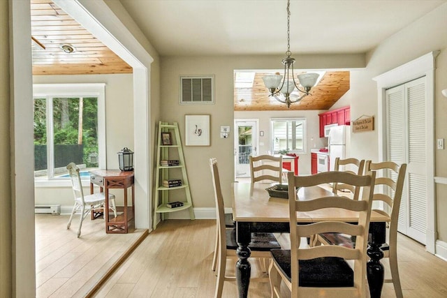 46210 Perkins Blvd, New Buffalo, MI 49117 - dining space with a chandelier, healthy amount of natural light, light wood-style floors, and a baseboard radiator