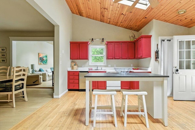 46210 Perkins Blvd, New Buffalo, MI 49117 - kitchen with reddish brown cabinets, dishwasher, vaulted ceiling, light wood finished floors, and a skylight