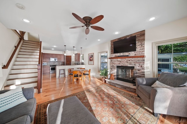 4078 Woodland Ave, Manitou Beach, MI 49253 - living room with light wood-type flooring, a ceiling fan, a fireplace, recessed lighting, and stairway