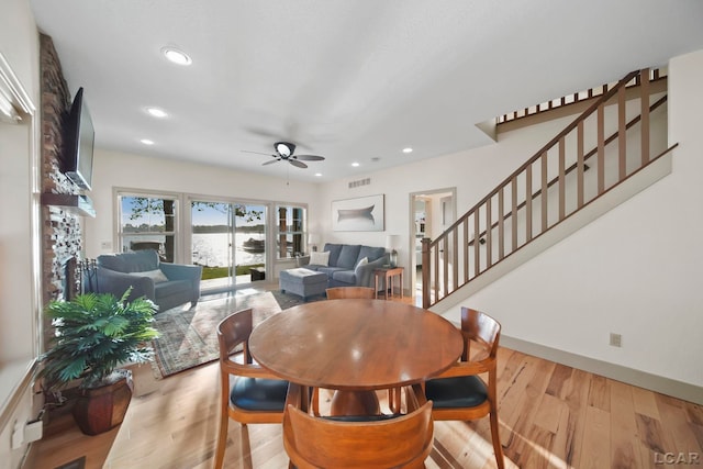 4078 Woodland Ave, Manitou Beach, MI 49253 - dining area featuring a fireplace, a ceiling fan, stairway, wood finished floors, and recessed lighting