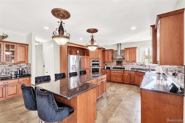 4303 S Lake Ln, Shelby Twp, MI 48316 - kitchen with stainless steel appliances, wall chimney exhaust hood, decorative backsplash, a kitchen island, and brown cabinetry