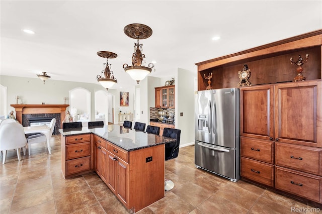 4303 S Lake Ln, Shelby Twp, MI 48316 - kitchen featuring stainless steel fridge, a premium fireplace, arched walkways, dark stone counters, and a kitchen island