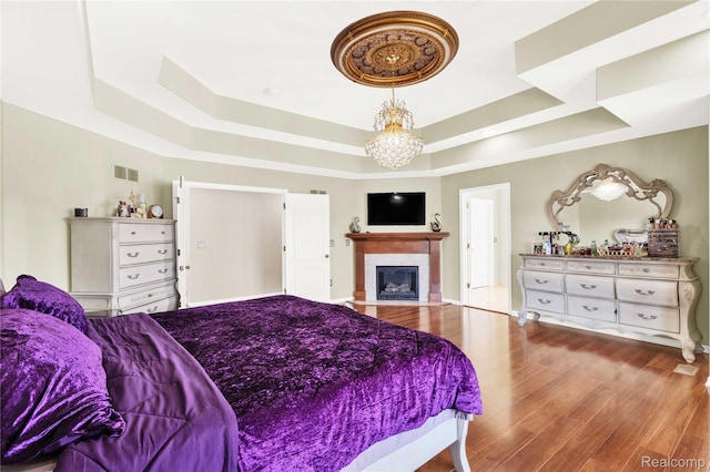 4303 S Lake Ln, Shelby Twp, MI 48316 - bedroom with a raised ceiling, a chandelier, wood finished floors, and a fireplace with flush hearth