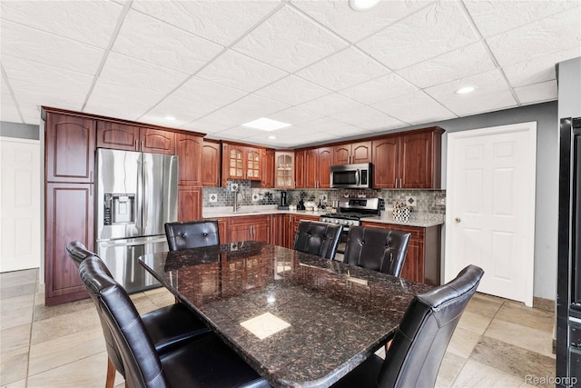 4303 S Lake Ln, Shelby Twp, MI 48316 - kitchen featuring appliances with stainless steel finishes, tasteful backsplash, a drop ceiling, glass insert cabinets, and a kitchen bar