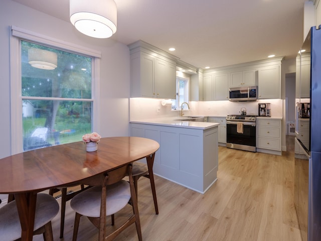3002 Applelane Ave, Kalamazoo, MI 49008 - kitchen featuring stainless steel appliances, light wood-style floors, a peninsula, light countertops, and recessed lighting