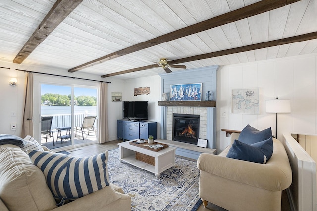 10520 Maple Xing, Canadian Lakes, MI 49346 - living room with a wooden ceiling with exposed beams, a glass covered fireplace, wood finished floors, and ceiling fan