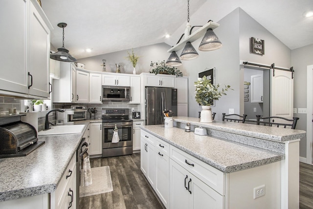 9733 E O Ave, Kalamazoo, MI 49048 - kitchen with stainless steel appliances, lofted ceiling, dark wood-type flooring, a kitchen island, and a barn door
