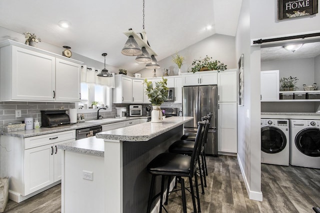 9733 E O Ave, Kalamazoo, MI 49048 - kitchen featuring freestanding refrigerator, washing machine and dryer, lofted ceiling, decorative backsplash, and white cabinets