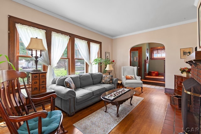 1044 Michigan Ave, Adrian, MI 49221 - living area with arched walkways, hardwood / wood-style floors, crown molding, and a brick fireplace