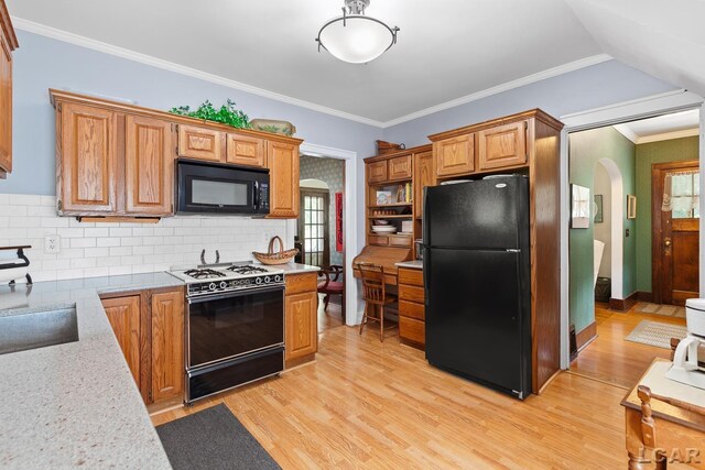1044 Michigan Ave, Adrian, MI 49221 - kitchen with black appliances, arched walkways, light wood finished floors, tasteful backsplash, and ornamental molding