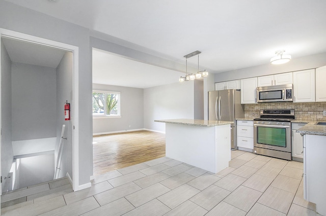 2375 Pontiac Trl, Ann Arbor, MI 48105 - kitchen with appliances with stainless steel finishes, backsplash, white cabinetry, a kitchen island, and wood finish floors