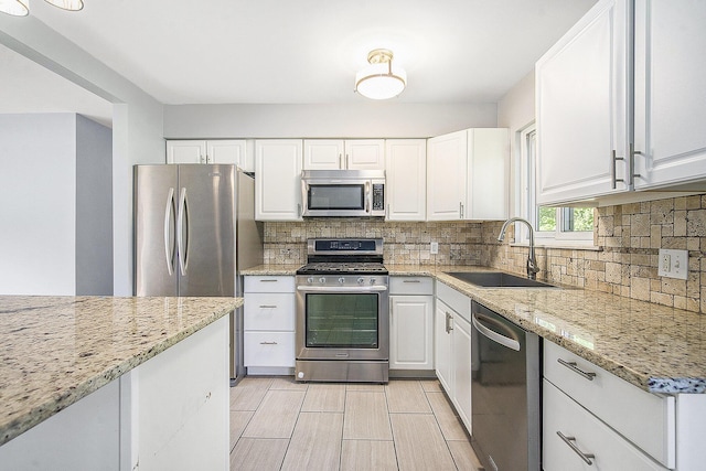 2375 Pontiac Trl, Ann Arbor, MI 48105 - kitchen featuring appliances with stainless steel finishes, white cabinets, backsplash, and light stone countertops