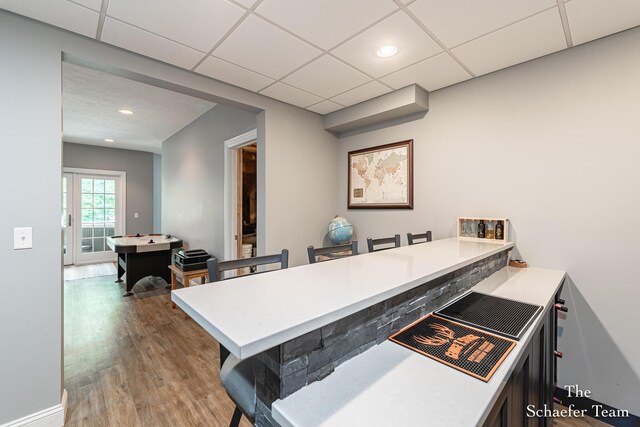 5264 Deverman Ct NE, Lowell, MI 49331 - kitchen featuring a breakfast bar, wood finished floors, light countertops, a peninsula, and a paneled ceiling