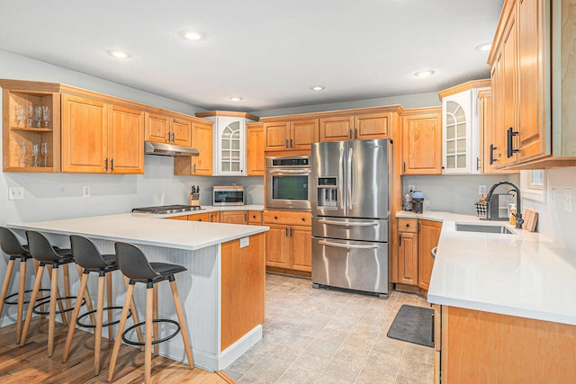 4166 Grandwood Cir, Saint Joseph, MI 49085 - kitchen featuring appliances with stainless steel finishes, under cabinet range hood, a peninsula, a breakfast bar, and glass insert cabinets