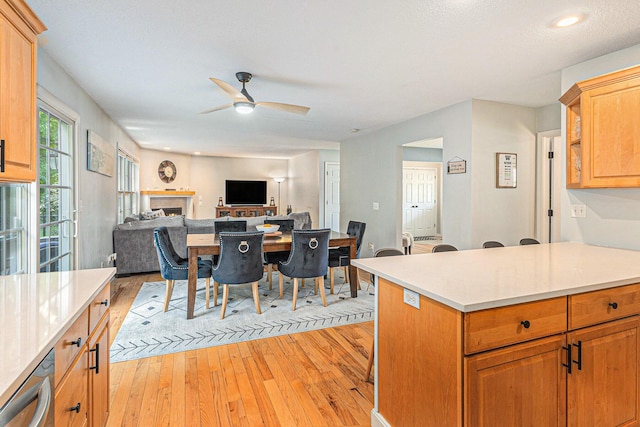 4166 Grandwood Cir, Saint Joseph, MI 49085 - kitchen with light wood-style flooring, a ceiling fan, light countertops, a warm lit fireplace, and recessed lighting