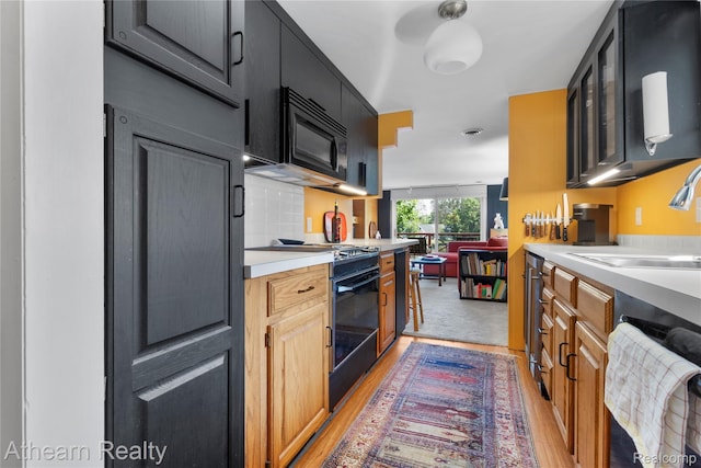6600 W Shore Dr, Weidman, MI 48893 - kitchen featuring black appliances, light countertops, light wood-style floors, and glass insert cabinets