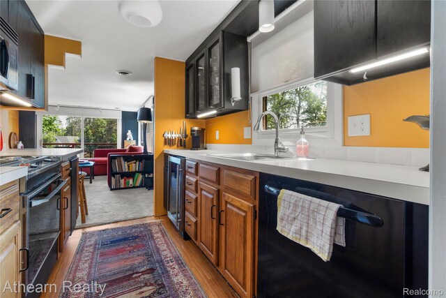 6600 W Shore Dr, Weidman, MI 48893 - kitchen featuring black appliances, beverage cooler, light countertops, light wood finished floors, and glass insert cabinets