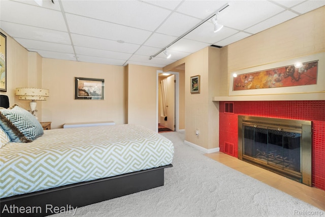 6600 W Shore Dr, Weidman, MI 48893 - bedroom featuring rail lighting, carpet, a fireplace with flush hearth, and a drop ceiling