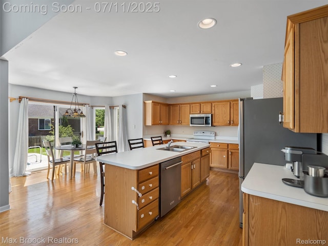 39104 Devonshire Ct, Harrison Township, MI 48045 - kitchen with appliances with stainless steel finishes, a kitchen island with sink, light countertops, brown cabinetry, and light wood-type flooring