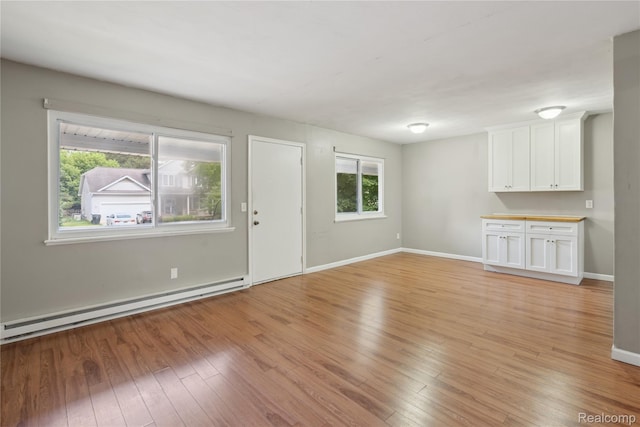 637 Lexington Ave, East Lansing, MI 48823 - unfurnished living room featuring a baseboard heating unit and light wood-type flooring