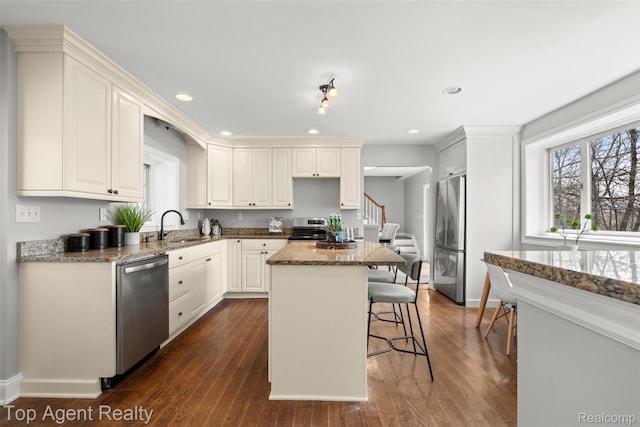 1593 Parke St, Rochester Hills, MI 48307 - kitchen with appliances with stainless steel finishes, a breakfast bar area, stone counters, a kitchen island, and dark wood finished floors