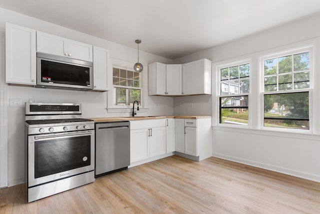 1680 Kalamazoo Ave SE, Grand Rapids, MI 49507 - kitchen with appliances with stainless steel finishes, light wood-type flooring, butcher block countertops, decorative light fixtures, and white cabinetry
