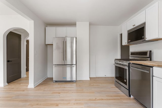 1680 Kalamazoo Ave SE, Grand Rapids, MI 49507 - kitchen with stainless steel appliances, white cabinetry, light wood-type flooring, arched walkways, and butcher block counters
