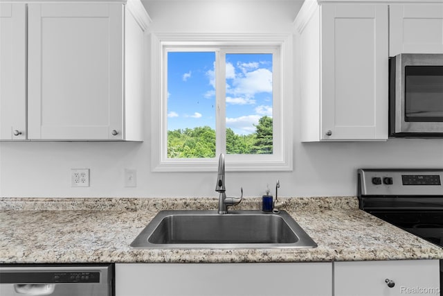 7900 Wiggins Rd, Howell, MI 48855 - kitchen featuring appliances with stainless steel finishes, white cabinets, and light stone countertops