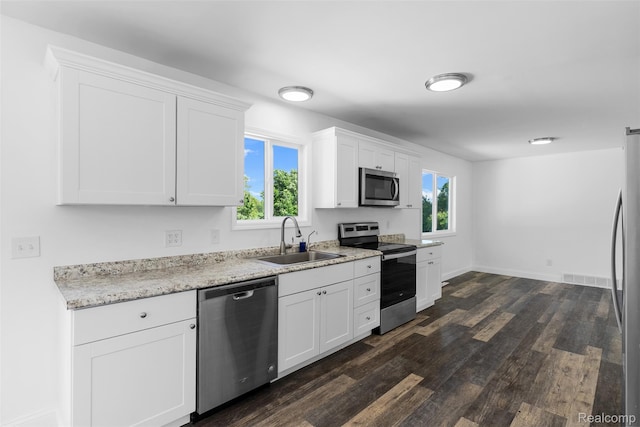 7900 Wiggins Rd, Howell, MI 48855 - kitchen with stainless steel appliances, dark wood-style floors, white cabinetry, and light stone countertops