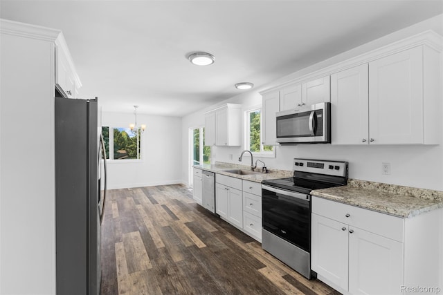 7900 Wiggins Rd, Howell, MI 48855 - kitchen with stainless steel appliances, a chandelier, dark wood-type flooring, white cabinets, and light stone counters