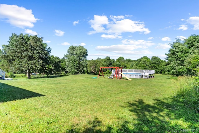 7900 Wiggins Rd, Howell, MI 48855 - view of green lawn with a playground and an outdoor pool