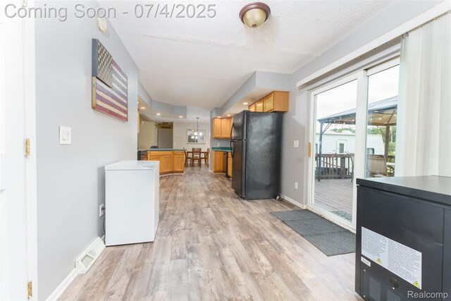 5771 Milett Rd, Fowlerville, MI 48836 - kitchen featuring freestanding refrigerator, refrigerator, light wood-style floors, dark countertops, and a textured ceiling