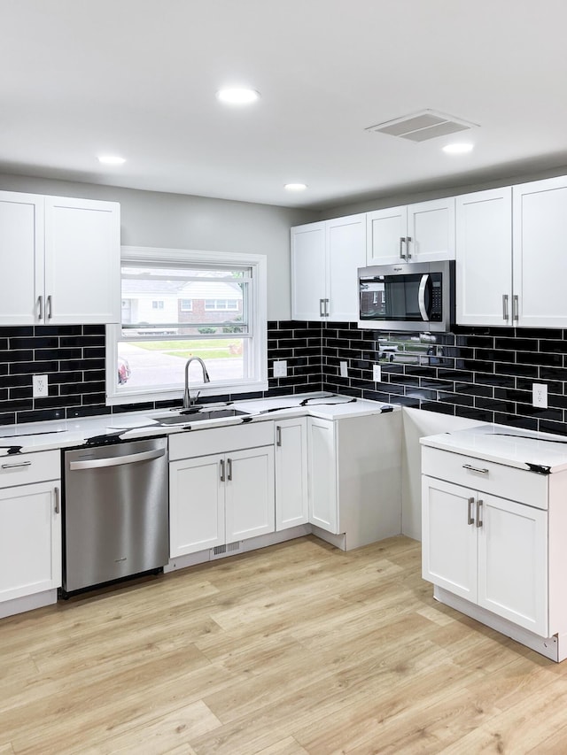 20283 Lancaster St, Harper Woods, MI 48225 - kitchen with stainless steel appliances, backsplash, white cabinetry, light wood-style flooring, and recessed lighting