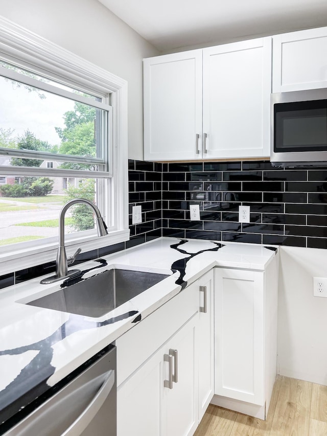 20283 Lancaster St, Harper Woods, MI 48225 - kitchen with appliances with stainless steel finishes, backsplash, white cabinets, and light wood-type flooring