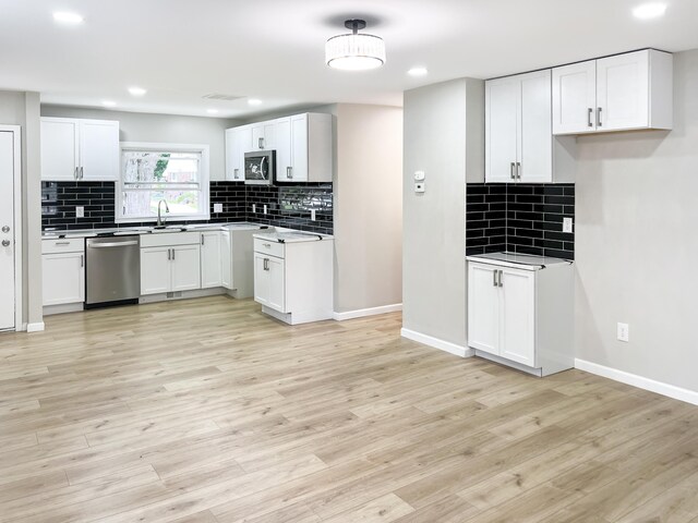 20283 Lancaster St, Harper Woods, MI 48225 - kitchen featuring appliances with stainless steel finishes, decorative backsplash, light wood finished floors, white cabinets, and recessed lighting