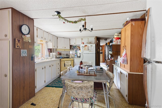 4175 Cherokee St, Gladwin, MI 48624 - kitchen featuring freestanding refrigerator, light floors, wood walls, range, and light countertops