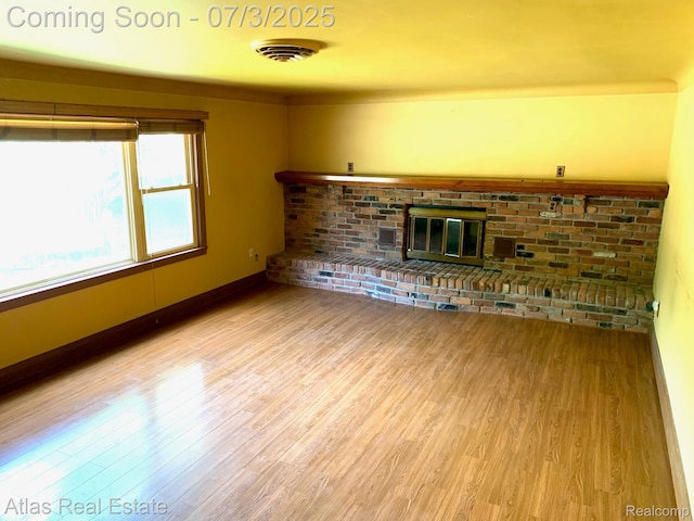 6201 S Main St, Clarkston, MI 48346 - unfurnished living room featuring light wood-style floors and a brick fireplace