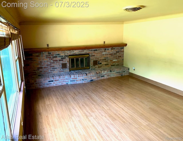 6201 S Main St, Clarkston, MI 48346 - unfurnished living room featuring a brick fireplace, wood finished floors, and plenty of natural light