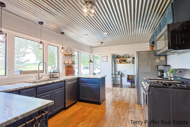 721 17 Mile Rd, Kent City, MI 49330 - kitchen featuring appliances with stainless steel finishes, light wood-style floors, light stone counters, decorative light fixtures, and a peninsula