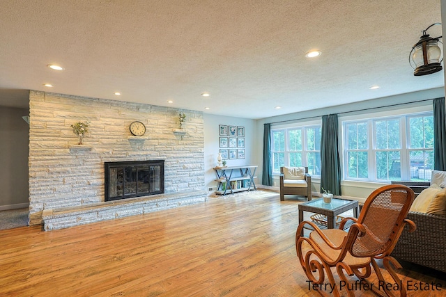 721 17 Mile Rd, Kent City, MI 49330 - living area featuring a textured ceiling, recessed lighting, hardwood / wood-style floors, and a stone fireplace