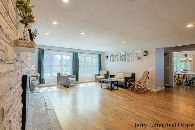 721 17 Mile Rd, Kent City, MI 49330 - living room featuring a textured ceiling, wood finished floors, recessed lighting, a chandelier, and a stone fireplace
