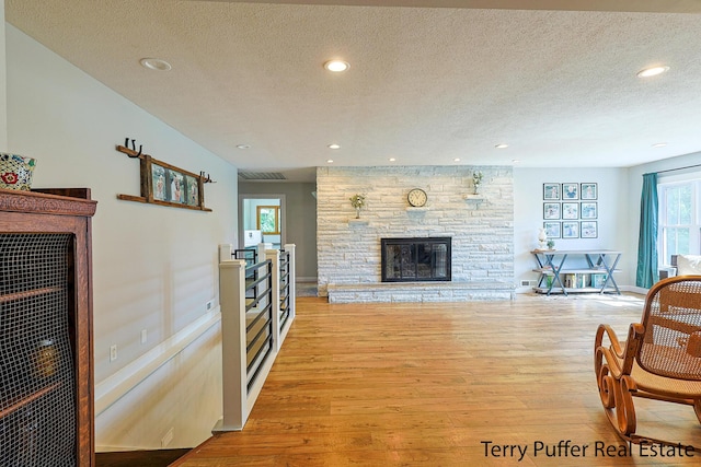721 17 Mile Rd, Kent City, MI 49330 - living room with light wood finished floors, a textured ceiling, a stone fireplace, and recessed lighting