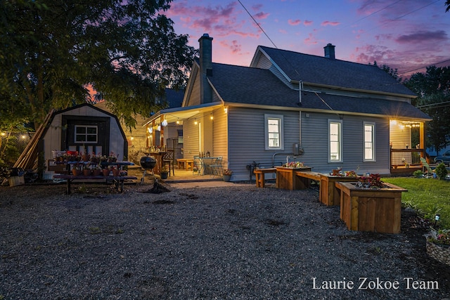 1101 White Ave NW, Grand Rapids, MI 49504 - rear view of property featuring a storage unit, a chimney, and a shingled roof