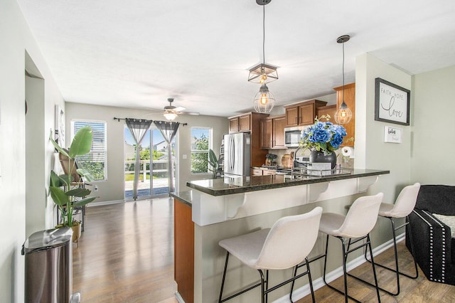 1619 Ives Mill Ln, Vicksburg, MI 49097 - kitchen featuring appliances with stainless steel finishes, brown cabinetry, wood finished floors, and a kitchen breakfast bar