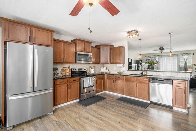 1619 Ives Mill Ln, Vicksburg, MI 49097 - kitchen featuring appliances with stainless steel finishes, a ceiling fan, a peninsula, brown cabinetry, and light wood finished floors