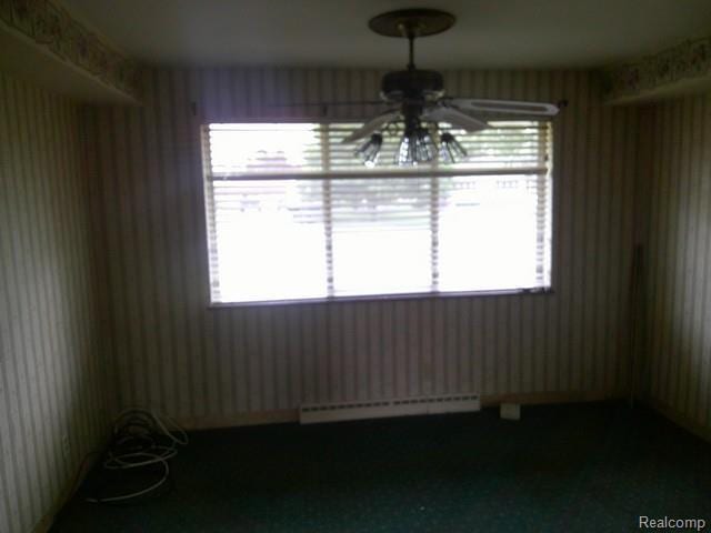 7776 Ash St, Birch Run, MI 48415 - unfurnished dining area featuring a baseboard heating unit, ceiling fan, wallpapered walls, and healthy amount of natural light