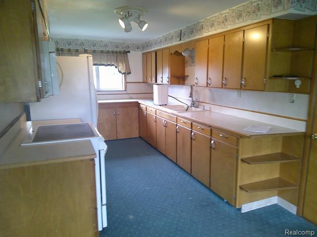 7776 Ash St, Birch Run, MI 48415 - kitchen featuring open shelves, white appliances, and brown cabinetry