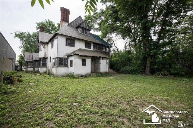 1989 W Grand Blvd, Detroit, MI 48208 - back of property with a chimney, a lawn, and stucco siding